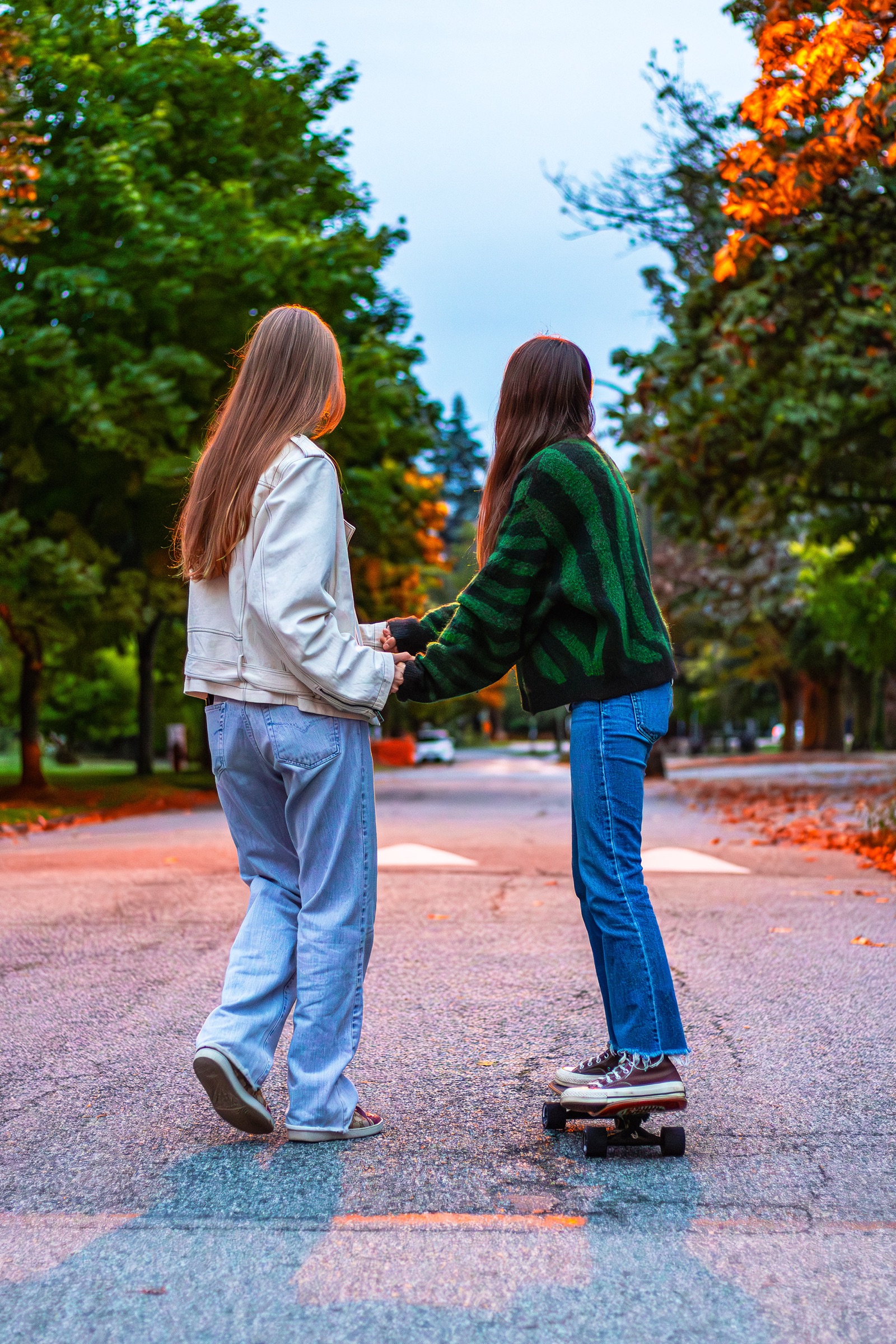 Couple holding hands on skateboards